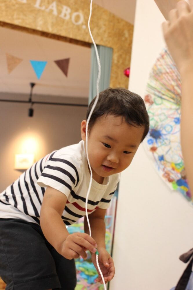 子どもがストローを紐に通している姿