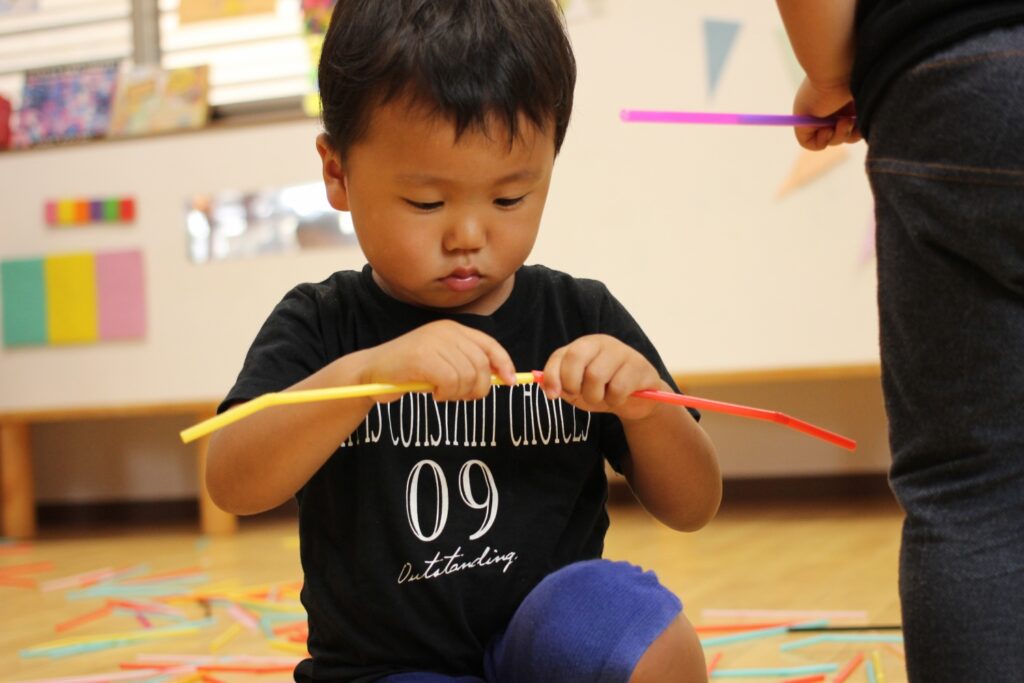 子どもがストローを繋げて遊んでいる様子