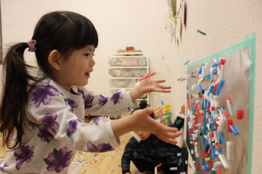 子どもがストローを壁に向かって投げて遊んでいる様子