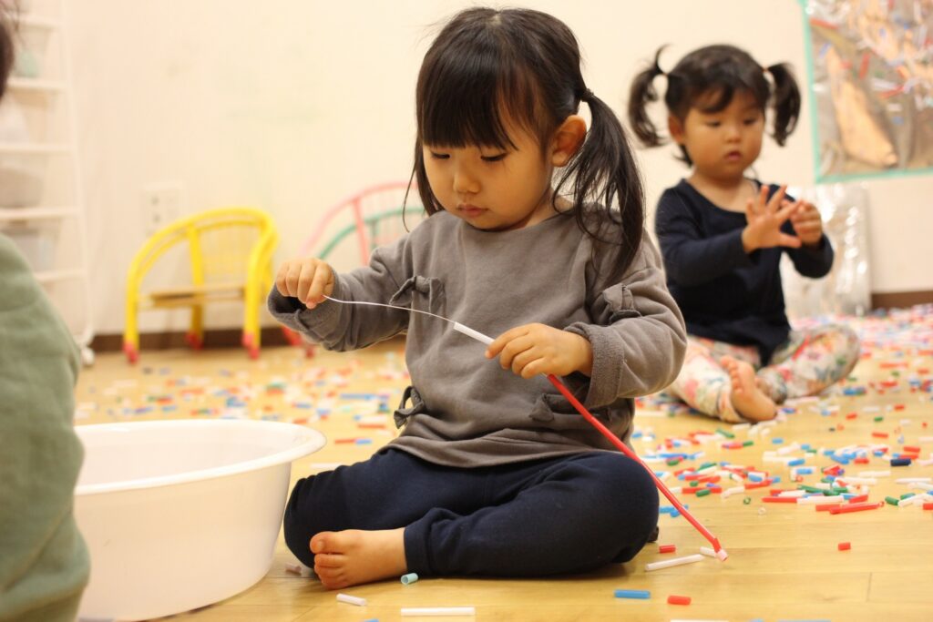 子どもがストローをワイヤーに通して遊んでいる様子