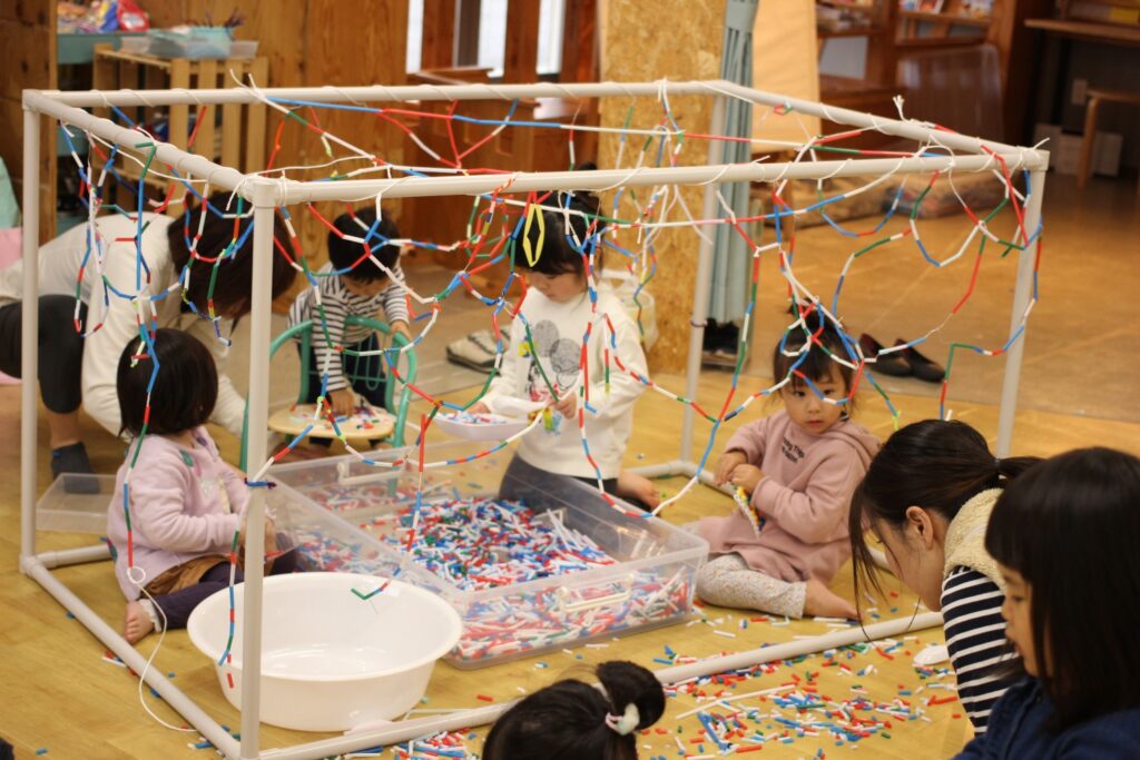 子どもたちで紐に通したストローでカーテンを作っている様子