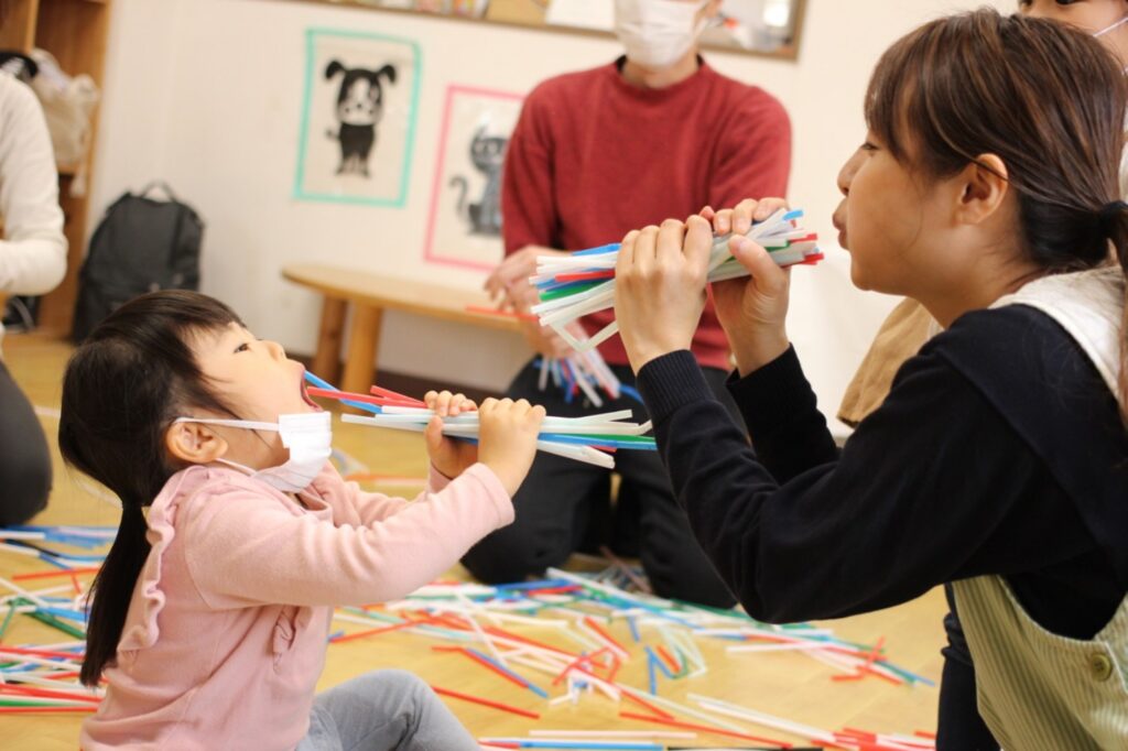 子どもがたくさんのストローを吹いている様子